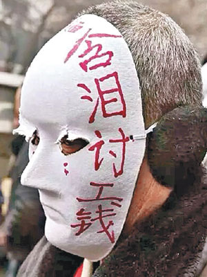 農民工戴着上寫有「含淚討工錢」等字句的面具討薪。（互聯網圖片）