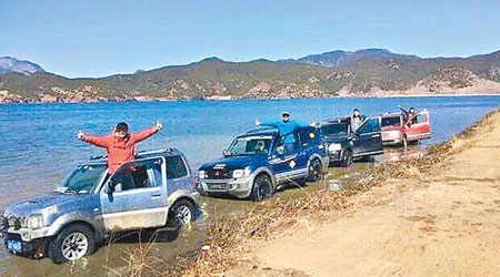 四輛越野車擅闖瀘沽湖淺水區，司機們開心拍照。（互聯網圖片）