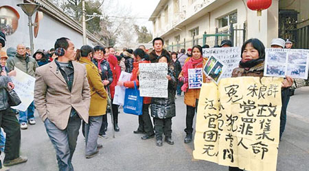 大批訪民高舉紙牌和抗議標語到信訪局請願。（互聯網圖片）