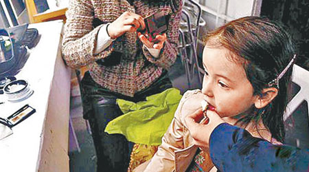 女童模為趕拍攝工作沒吃早餐，其母在她化妝時餵麵包。（互聯網圖片）