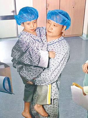 在肝臟移植手術前，肖坤慶抱起兒子準備接力捐肝。（互聯網圖片）