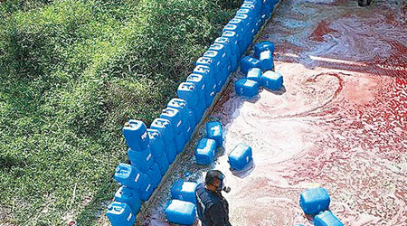工人擺塑膠桶陣阻止紅色液體流向其他地方。（互聯網圖片）
