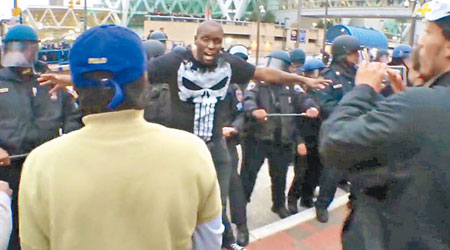 黑人男子張開手臂分隔警員與示威者。（互聯網圖片）