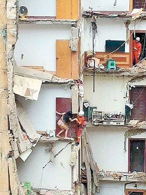 消防員拯救緊貼牆壁待救的女子。（互聯網圖片）