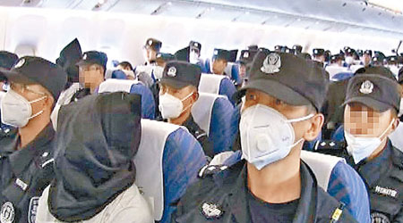 遣返回國的偷渡者乘搭飛機時被蒙頭扣押，身穿印有不同號碼的上衣。（互聯網圖片 ）
