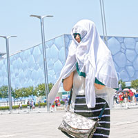 外出民眾以衣服蓋頭防曬。（中新社圖片）