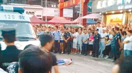 貴州<br>一名維族商販倒臥在地上，大批民眾包圍城管人員。（互聯網圖片）