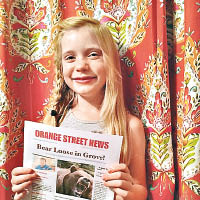 利西亞克拿着自己發行的《橘街新聞報》，一臉自信。（互聯網圖片）