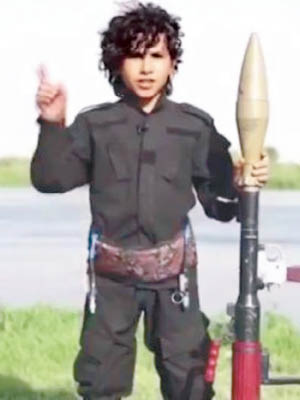 身穿迷彩服的男孩左手持火箭炮彈。