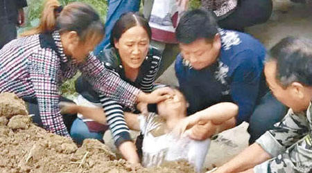 家屬一臉迫切，拉出被埋土中的孫秋英。（互聯網圖片）