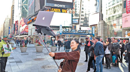 在紐約街頭舉起MacBook自拍，極受途人注目。（互聯網圖片）