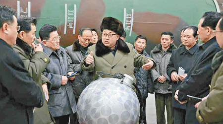 金正恩（中）站在疑似小型核彈頭模型前面。（勞動新聞）