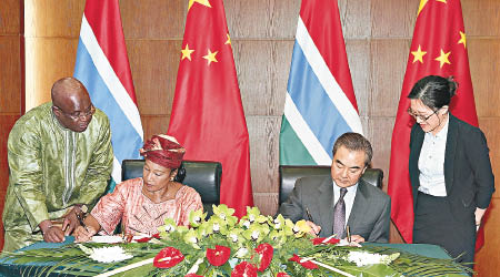 中國外長王毅（右二）與岡比亞外長（左二）簽署復交文件。（中新社圖片）