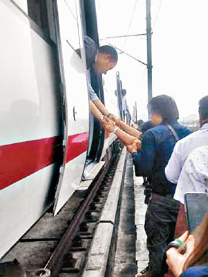 乘客協助被困者逃出車廂。（互聯網圖片）