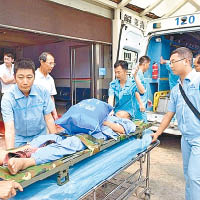 急病工人抵達海南後，即被抬上救護車。