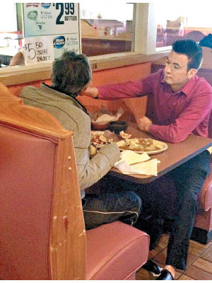 魯伊斯（右）親手餵無手的顧客食飯。（互聯網圖片）