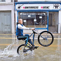 有居民踏單車在水浸的街頭飛馳。