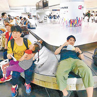 旅客躺在行李轉盤上休息。（中時電子報圖片）