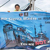 志願者在船上展示菲律賓坐灘軍艦的海報。