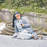 受傷的修女坐在路邊用電話。