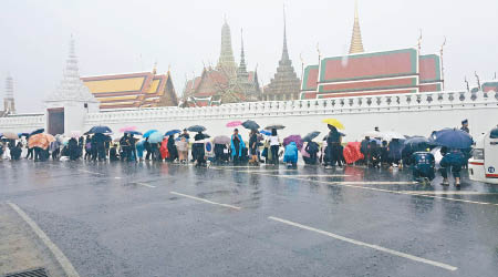 大批民眾默默地撐起雨傘，在大王宮外排隊。（互聯網圖片）