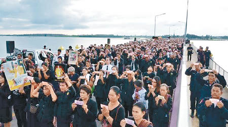 民眾手持泰王畫像唱歌。（互聯網圖片）