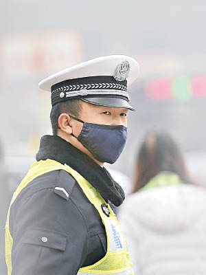 交通警員在霧霾中戴口罩執勤。（資料圖片）
