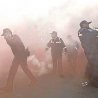 抗議人士投出煙霧彈，警員用手掩鼻。（中時電子報圖片）