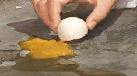 在發燙地面上煎雞蛋，十分鐘後蛋黃已有幾成熟。（電視畫面）