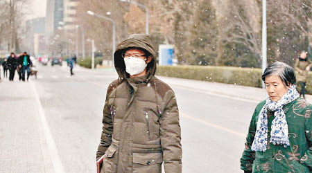 北京降雪，市民穿厚衣戴口罩出門。（互聯網圖片）
