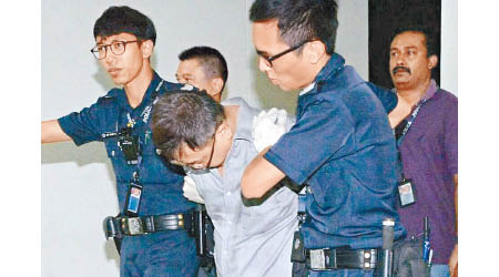 張錦興（中）被警員押走。（新加坡《新明日報》圖片）