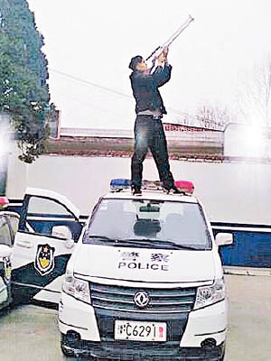 男子手持長槍站在警車車頂。（互聯網圖片）