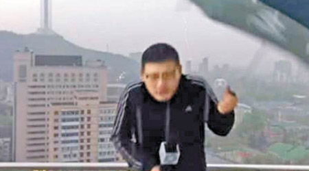 劉曉東冒雨在戶外報道，疑因觸電將手上的傘扔掉。