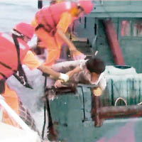 海巡隊隊員跳到漁船甲板，並把漁民拉住，免他墮海。