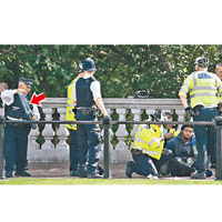一名黑人男子在倫敦白金漢宮附近持刀遊蕩被捕，警員沒收刀具（箭嘴示）。