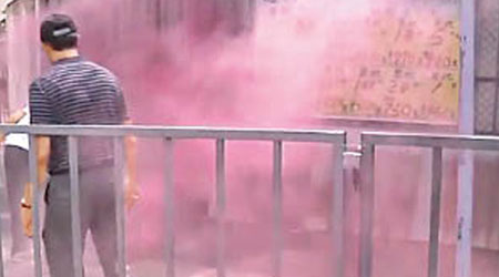 有民眾投擲煙霧彈，現場飄散粉紅色煙霧。（電視畫面）