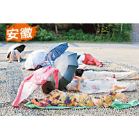 在淮北，有大媽打傘並躺臥地上做「熱療」。（互聯網圖片）
