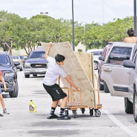 一名民眾搬運木板，在馬路中穿梭。