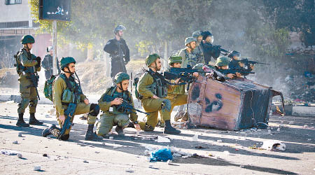 以色列士兵舉槍指向巴人。（美聯社圖片）