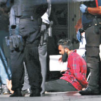 另一名紅衣疑犯被捕後坐在路旁。（互聯網圖片）