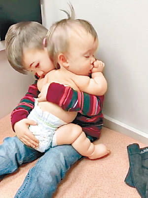 男童貼心抱着年幼妹妹。