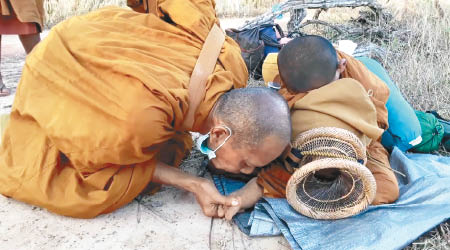 泰國僧人（左）為小沙彌的腳吹沙。（互聯網圖片）