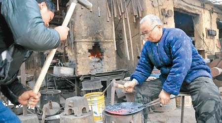 牛祺聖父子示範打造鐵鑊。