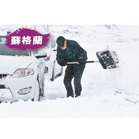 一名男子趕緊清理座駕旁的積雪。