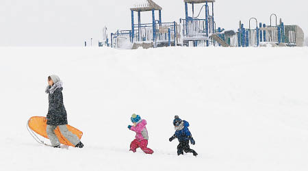 成人帶着小孩子雪中作樂。（美聯社圖片）