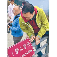有操廣東話的遊客跨過欄杆拍照。