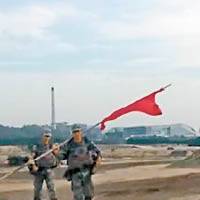 兩名手持紅旗的解放軍人員驅趕現場傳媒。