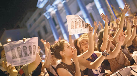民眾舉起印有一眾被告頭像的紙張。（美聯社圖片）