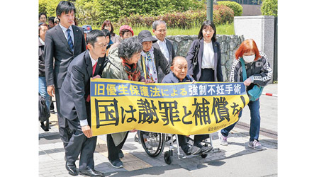 小島喜久夫（坐輪椅者）到法院提告。（美聯社圖片）