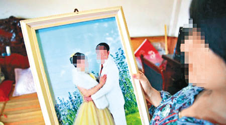 死者女兒手持父母婚照，神情哀傷。（互聯網圖片）